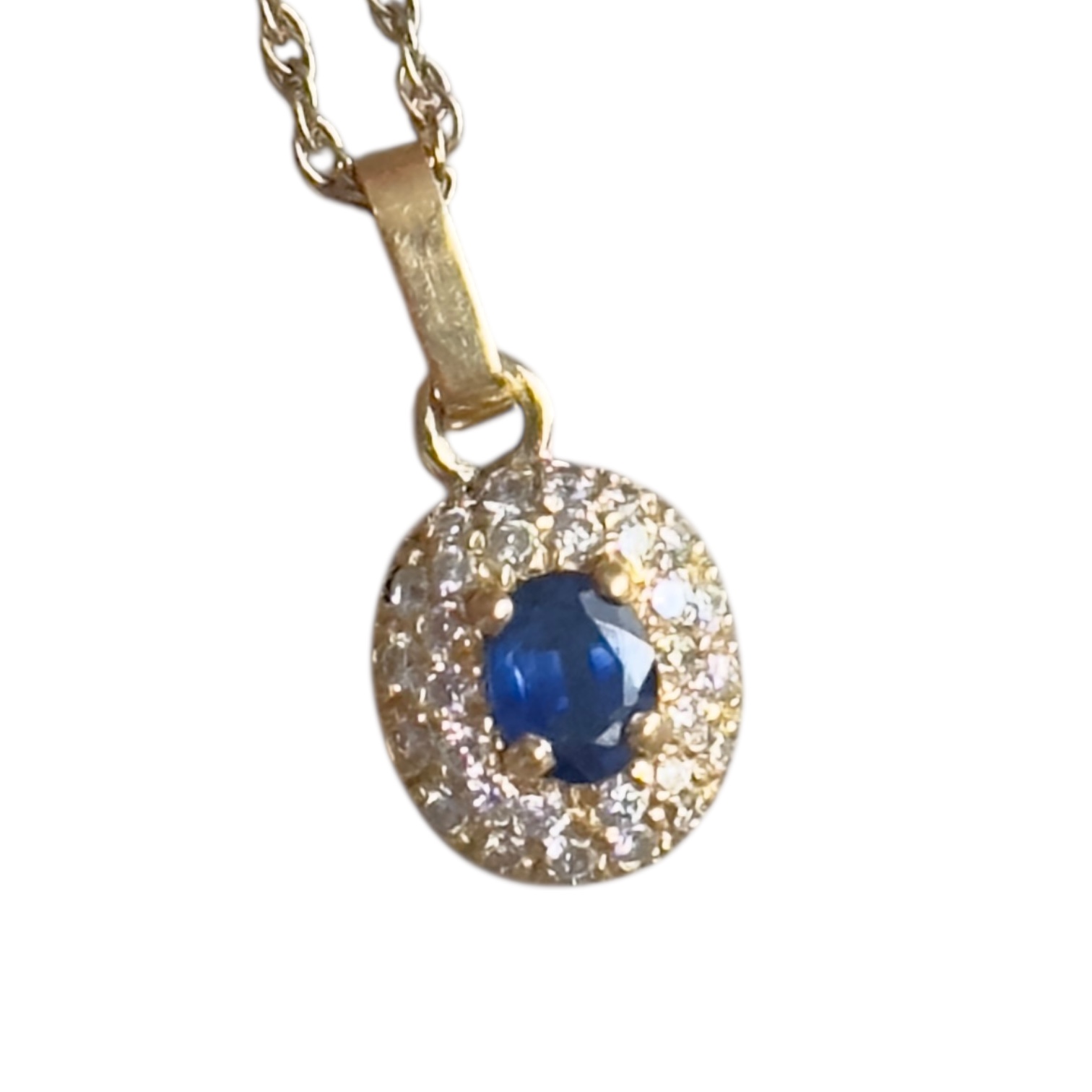 Pendentif or 18 carats saphir ovale entourage diamants | Des Bijoux en Or Pendentif en or jaune 18 carats avec saphir et diamants, présenté dans la main pour l’échelle.